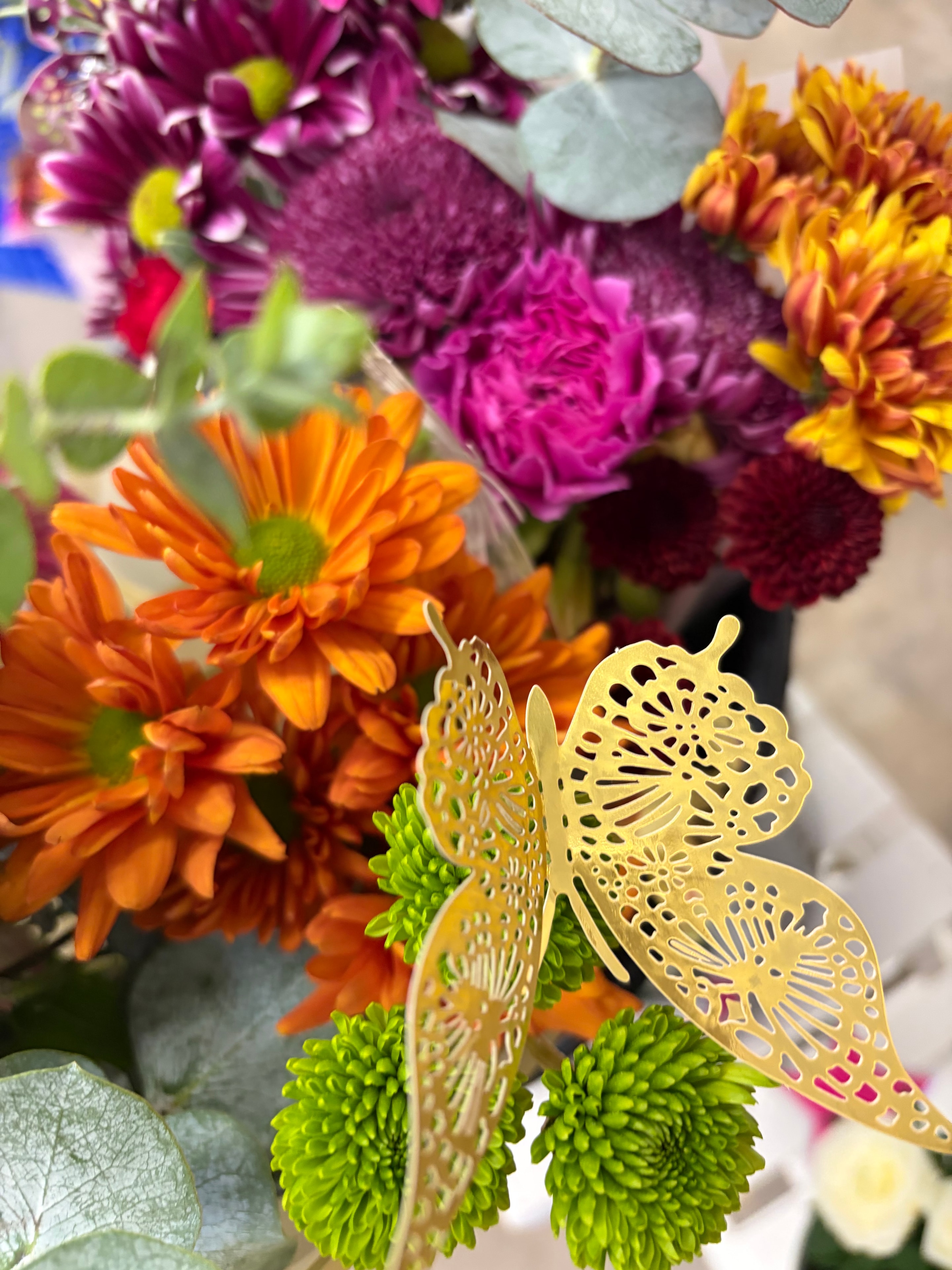Gold butterfly ornament on colorful chrysanthemum bouquet